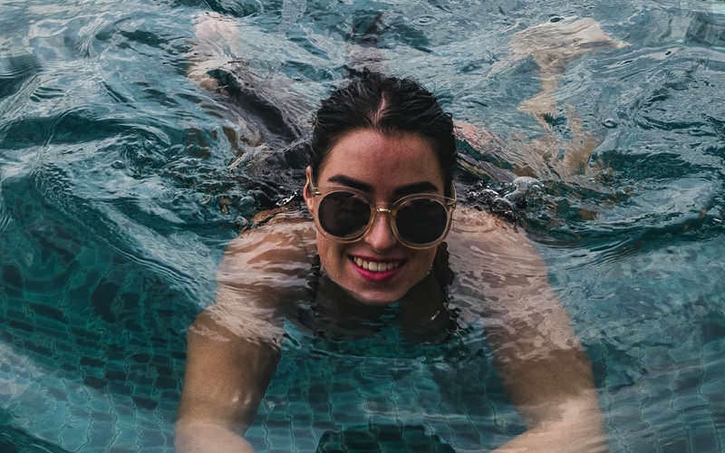woman with sunglasses swims in pool