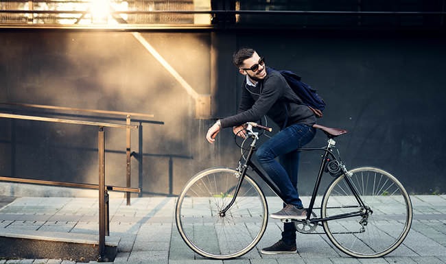 Historically Adventurous business man sits on his bicycle on city sidewalk